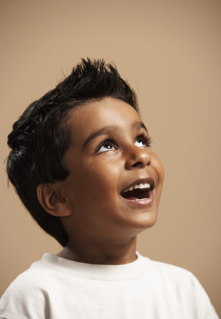 Boy (4-5) smiling, looking up, studio shot